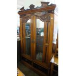 An Edwardian satinwood twin mirrored door wardrobe with inlaid and carved darker panels,