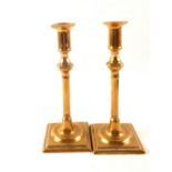 A pair of 18th Century seamed brass candlesticks with knopped cylindrical stems and square bases,
