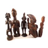 A New Guinea figure with shell eyes plus four African tribal figures