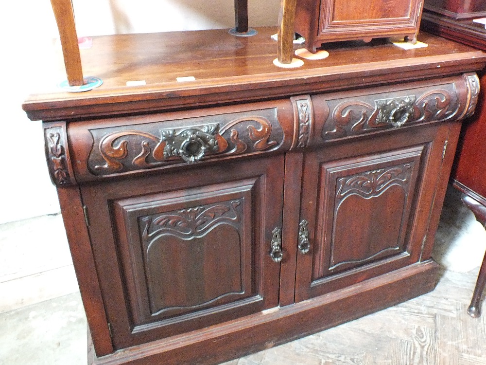 A carved Art Nouveau mahogany sideboard with two drawers and doors