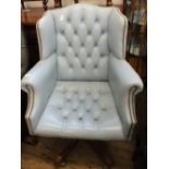 A sky blue leather button back swivel armchair