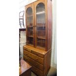 A modern pine glazed bookcase with chest of two short and three long drawers