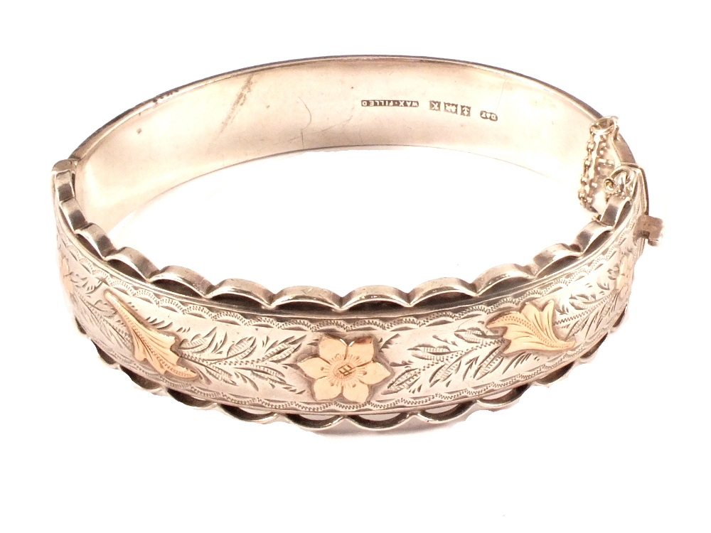A silver bangle with yellow metal overlay flowers (bangle is wax filled)