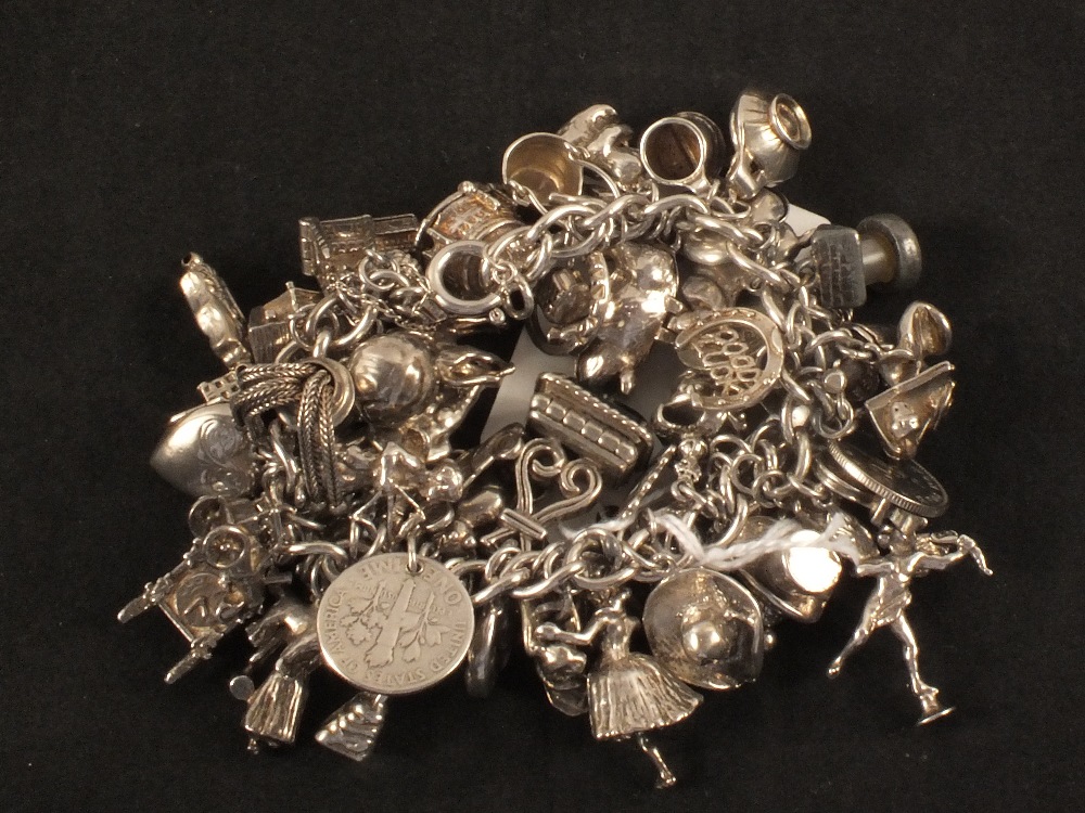 A charm bracelet with a large quantity of silver and white metal charms