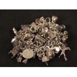 A charm bracelet with a large quantity of silver and white metal charms