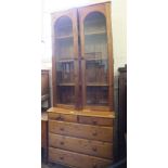 A modern pine glazed bookcase with chest of two short and three long drawers