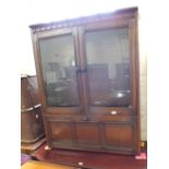 A dark Ercol style two door glazed bookcase with storage below