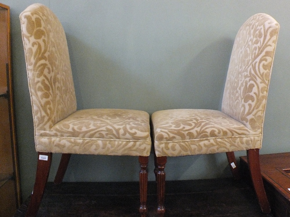 A set of four mahogany dining chairs with beige floral upholstery on fluted legs