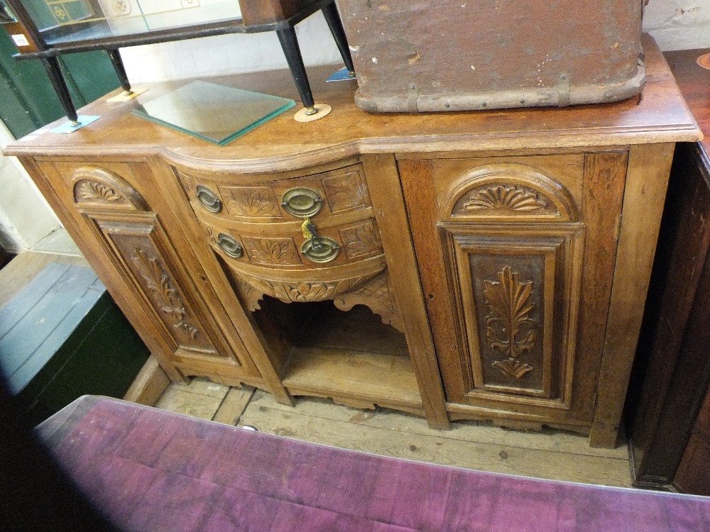 A shaped front oak sideboard with two central doors and two central drawers