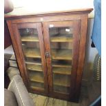 A stained pine two door glazed school stationary cupboard marked "Educational Supply,