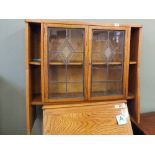 A light oak floor standing lead glazed two door display cabinet flanked by narrow shelves