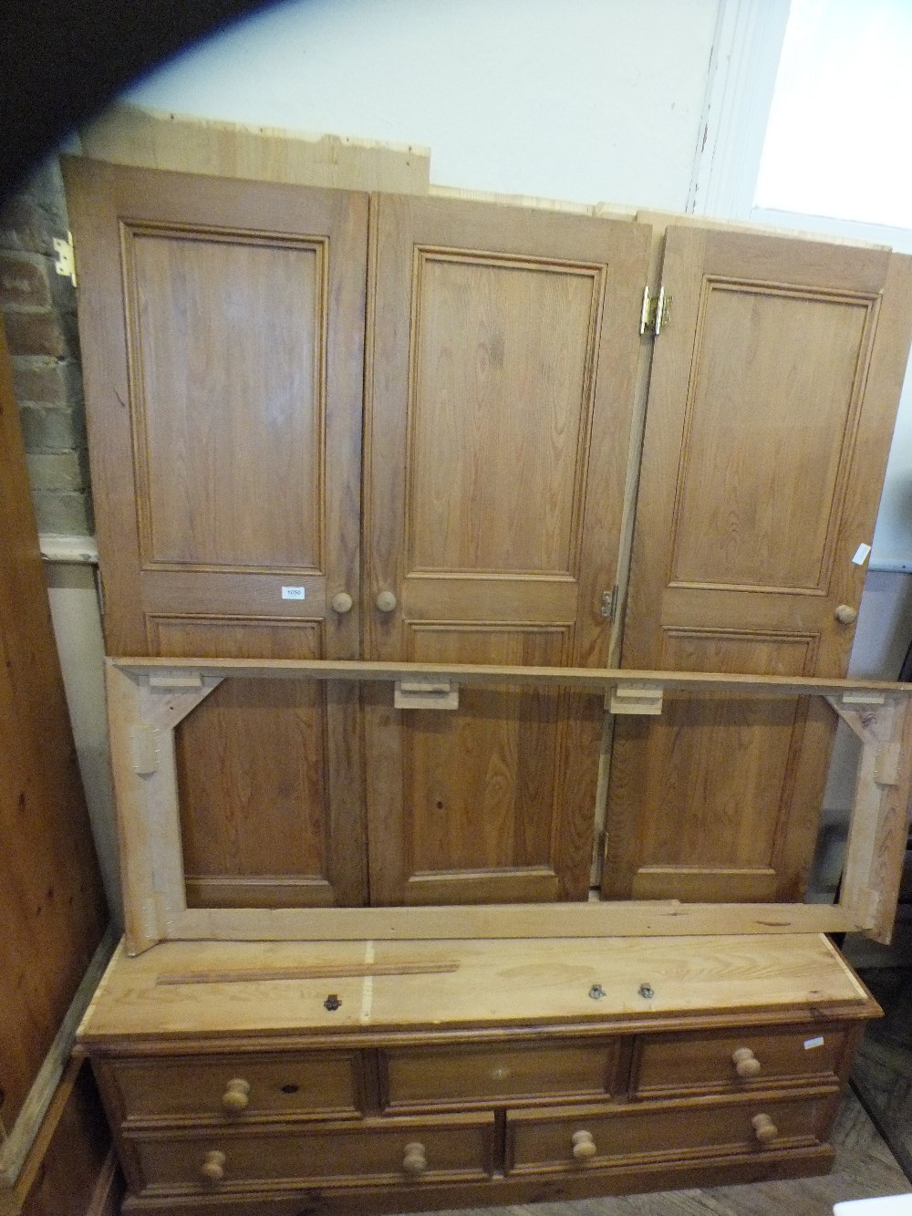 A pine triple wardrobe on five drawer base