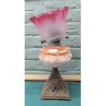 An iron and pink glass oil lamp plus a non-matching pink and etched glass shade