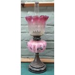 A brass column oil lamp with pink floral bowl and shade