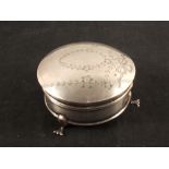 A circular silver trinket box with engraved floral detail to lid,