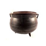 A heavy antique bulbous cast iron cauldron with ribbed decoration,