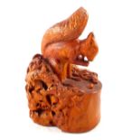 A carved wooden squirrel and nut sculpture,
