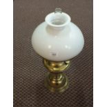 A brass oil lamp with milk shade and glass funnel