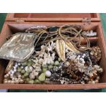 A wooden box containing costume jewellery including beads, necklaces,