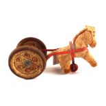 A tin plate roller bell pulled by a stuffed felt horse