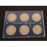 Six cased US silver dollars,