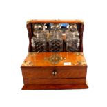 An oak three bottle Tantalus with silver plated fittings,