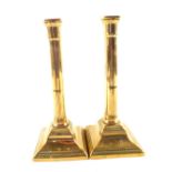 A pair of 18th Century brass candlesticks with part fluted cylindrical stems and beaded square