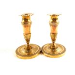 A pair of early 19th Century French brass and copper candlesticks with circles of fluted and chased