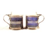 A matched pair of silver mustard pots with pierced design and crested lids,