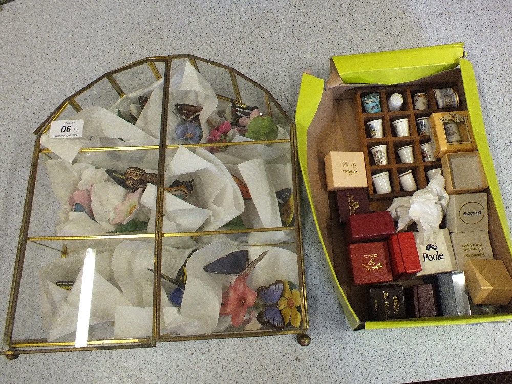 A display case of decorative ceramic butterflies plus various thimbles