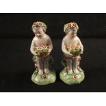 A pair of 19th Century porcelain putto with flowers, blue anchor mark,