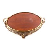 An oval mahogany tray having pierced brass surround with integral twin handles and four feet,