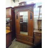 An Art Nouveau wardrobe with single mirror door and unusual carved fretwork and glass panels