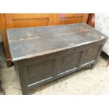 A dark stained oak coffer with three carved panels to the front