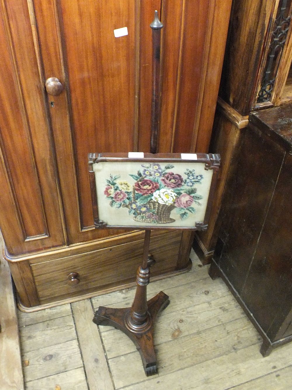 An adjustable rosewood pole firescreen on tripod base with woolwork and beaded screen