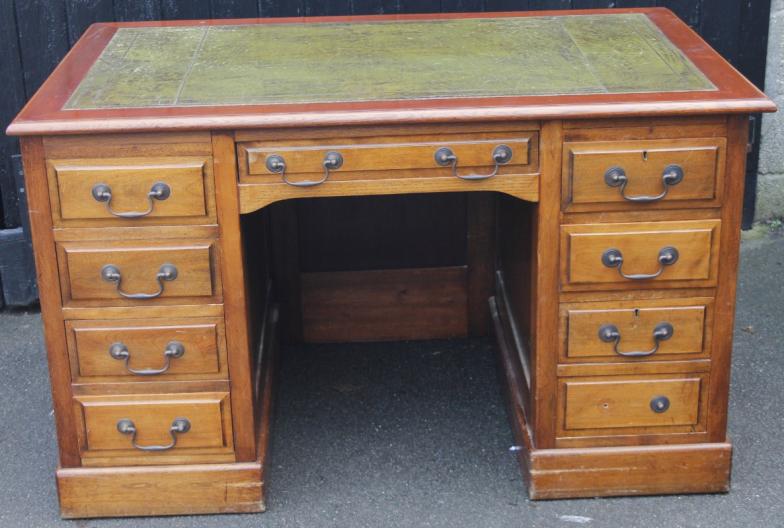 A 20thC mahogany finish writing desk, the rectangular moulded overhanging top with one piece part