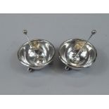 A pair of George V circular silver open salts, with bun feet, and a pair of matching spoons,