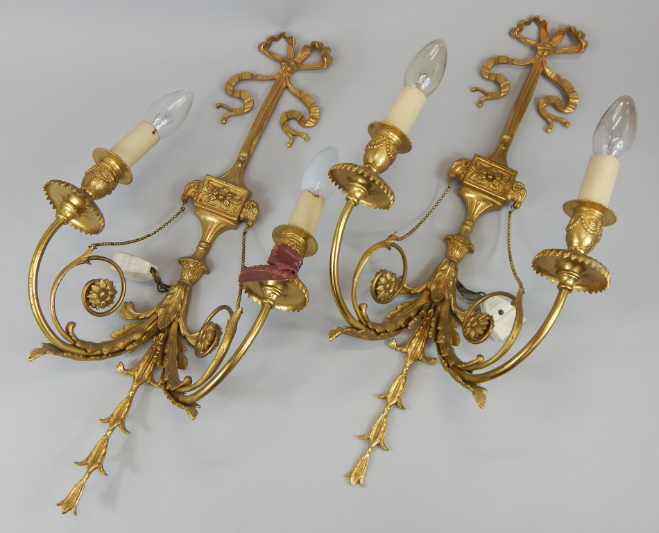 A pair of gilt metal two branch wall lights, cast with lion masks, flowers, leaves, bows, etc, in