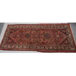 A Persian style rug, in a floral pattern, predominately in red and green, 102cm x 203cm
