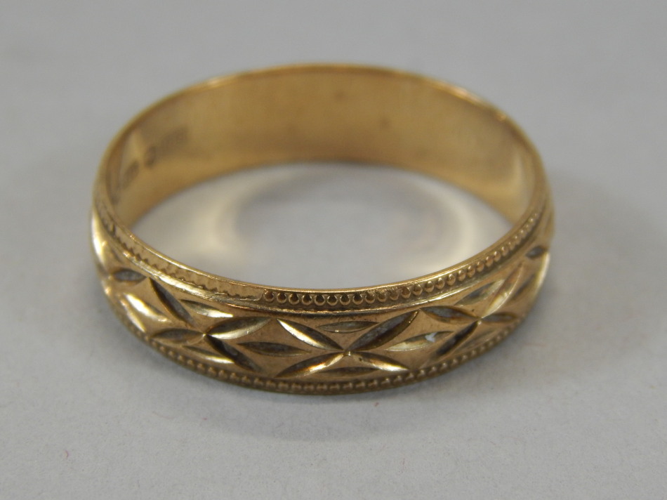A wedding band, of part textured geometric outline, yellow metal, marked 375