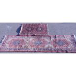 A Persian style rug, in geometric pattern, predominately in red and blue, with tasselled end,