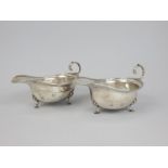 A pair of George V silver sauce boats, each with four cabriole legs, with pad feet and shell
