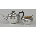 A George V oval silver teapot, with ebonised knop and handle, and an associated similar two