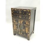 A 19thC oriental black lacquered cabinet, decorated to the front with figures, leaves, buildings