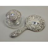 Two silver mounted items, dressing table mirror with embossed decoration and a cut glass powder