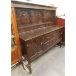 A 20thC stained oak sideboard, the raised panelled back carved with arches, the base with two