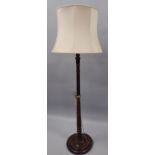 A turned and stained beech standard lamp, on a circular base, with shade. Provenance: