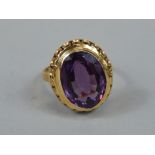 A ladies dress ring, of chunky design, with oval purple stone, on a part pierced setting and part