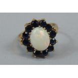 A ladies dress ring, florally set with central claw set opal, surrounded by small blue sapphire