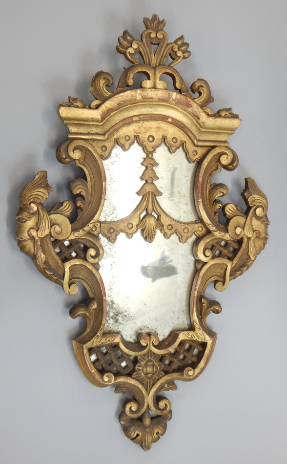 A 19thC giltwood wall mirror, of cartouche form decorated with scrolls, masks, flowers, etc, 89cm